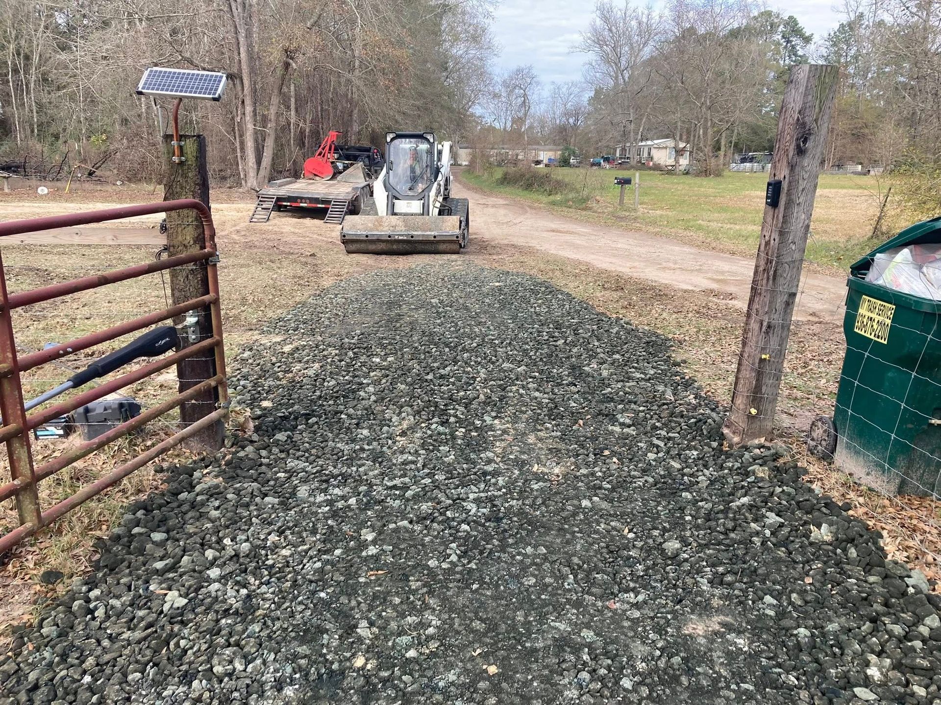 A bulldozer is moving gravel on a dirt road.