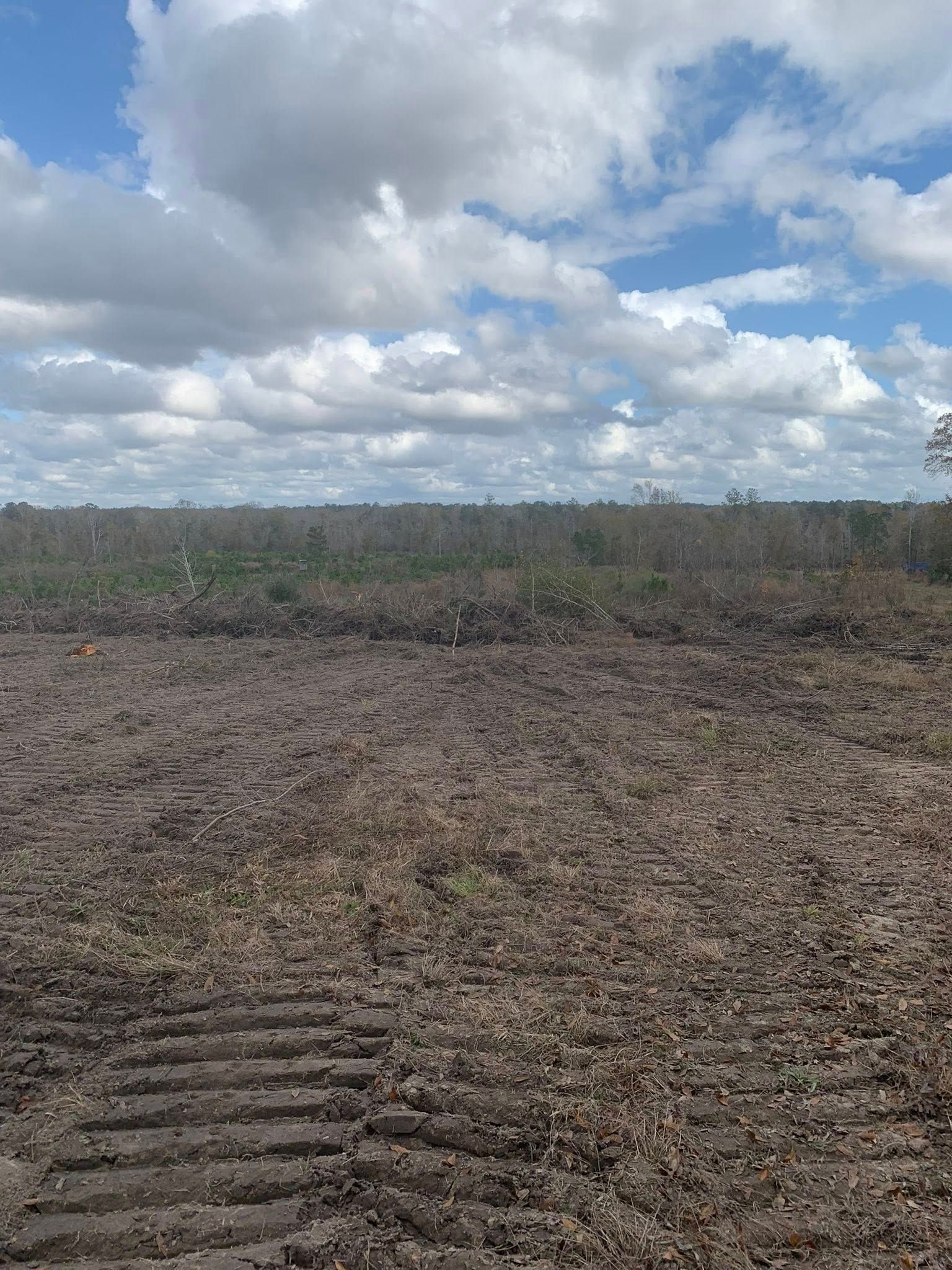 A large dirt field with a blue sky and clouds in the background.