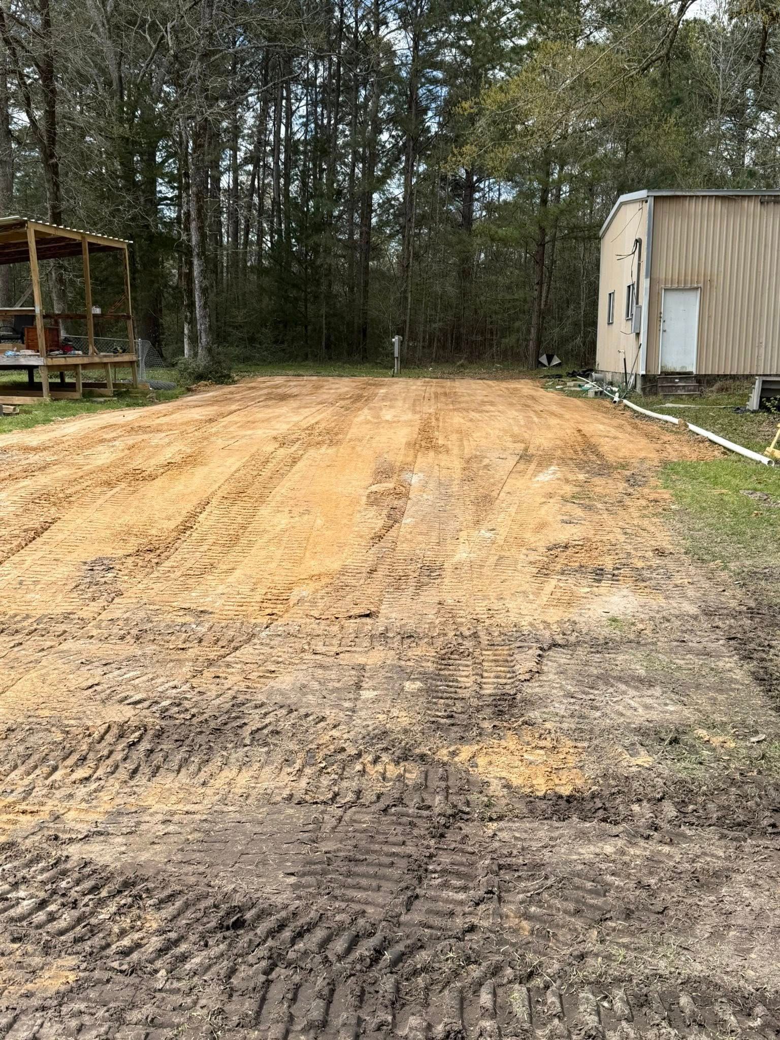 A dirt road with a house in the background and trees in the background.