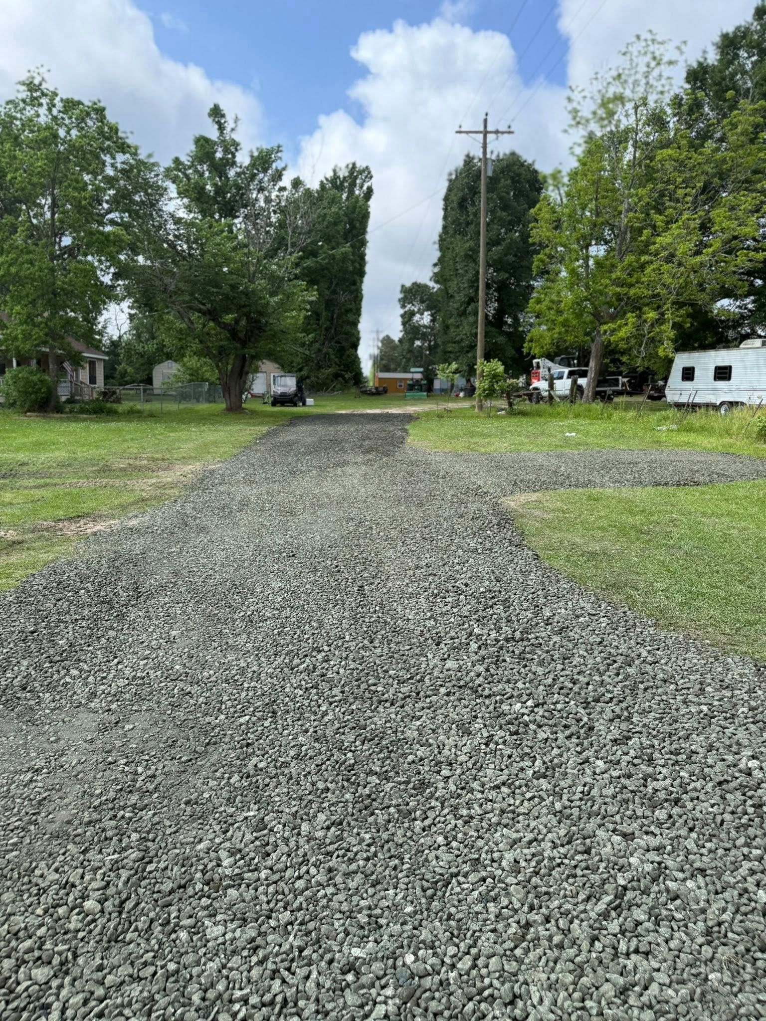 A gravel road going through a grassy field.