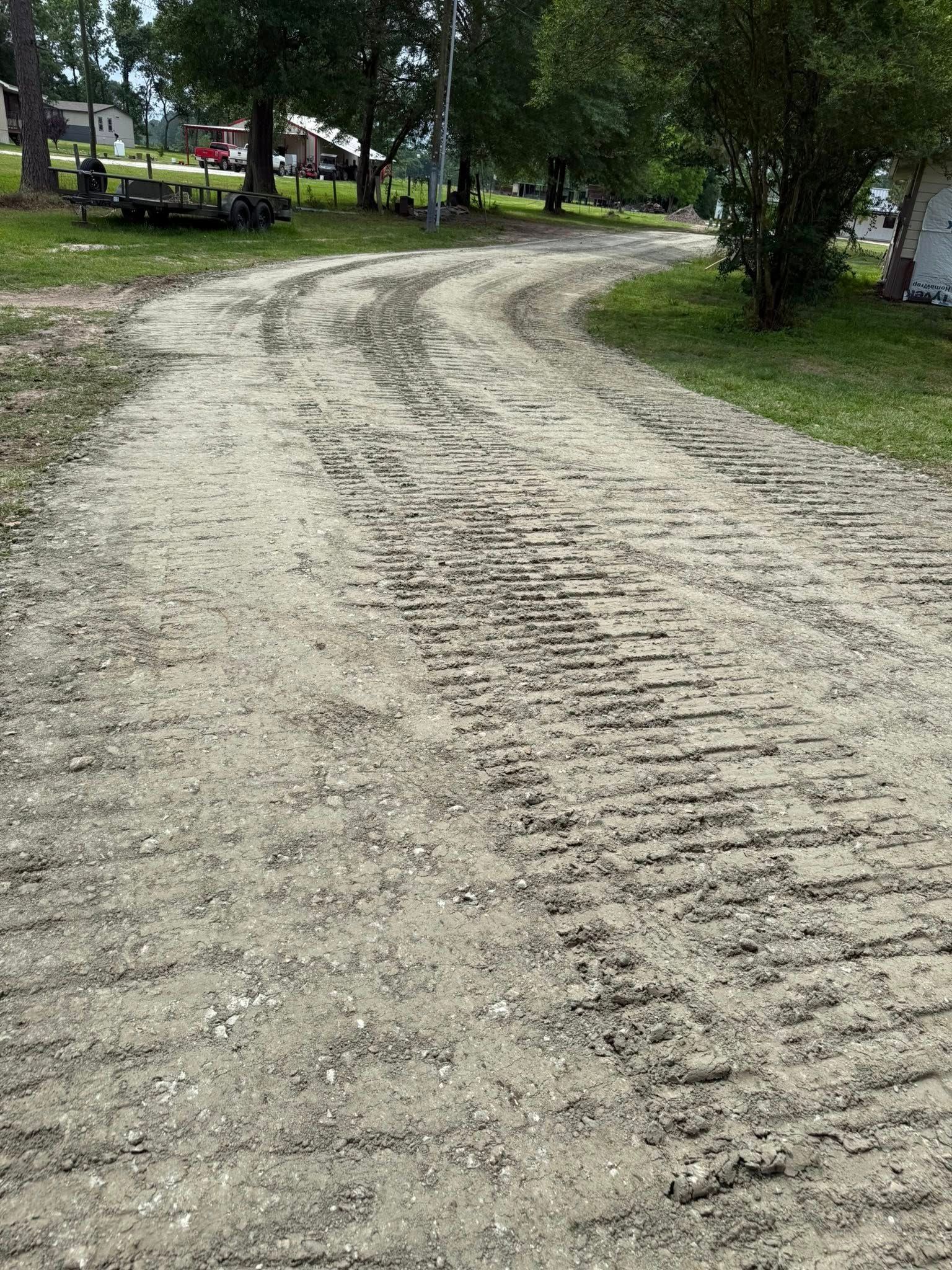 A dirt road going through a park with trees on both sides.