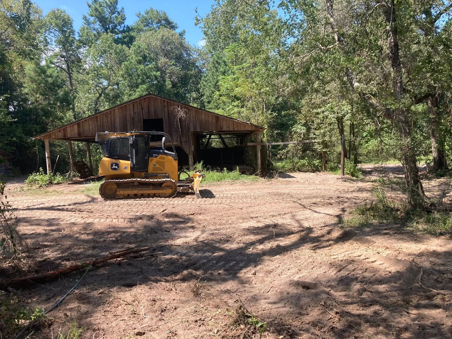 A bulldozer is sitting in a dirt field in front of a wooden building.