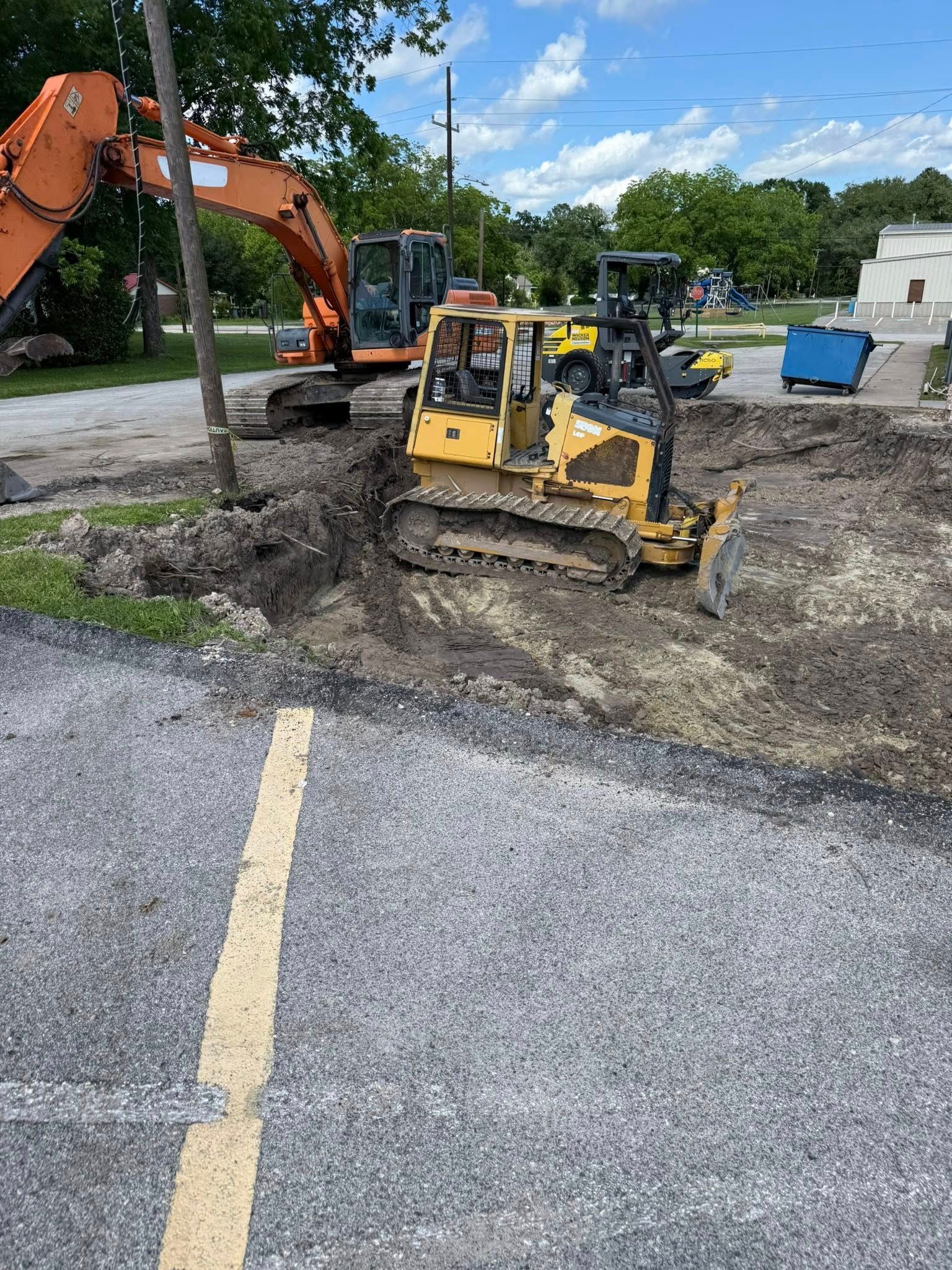 A bulldozer is digging a hole in the ground in a parking lot.