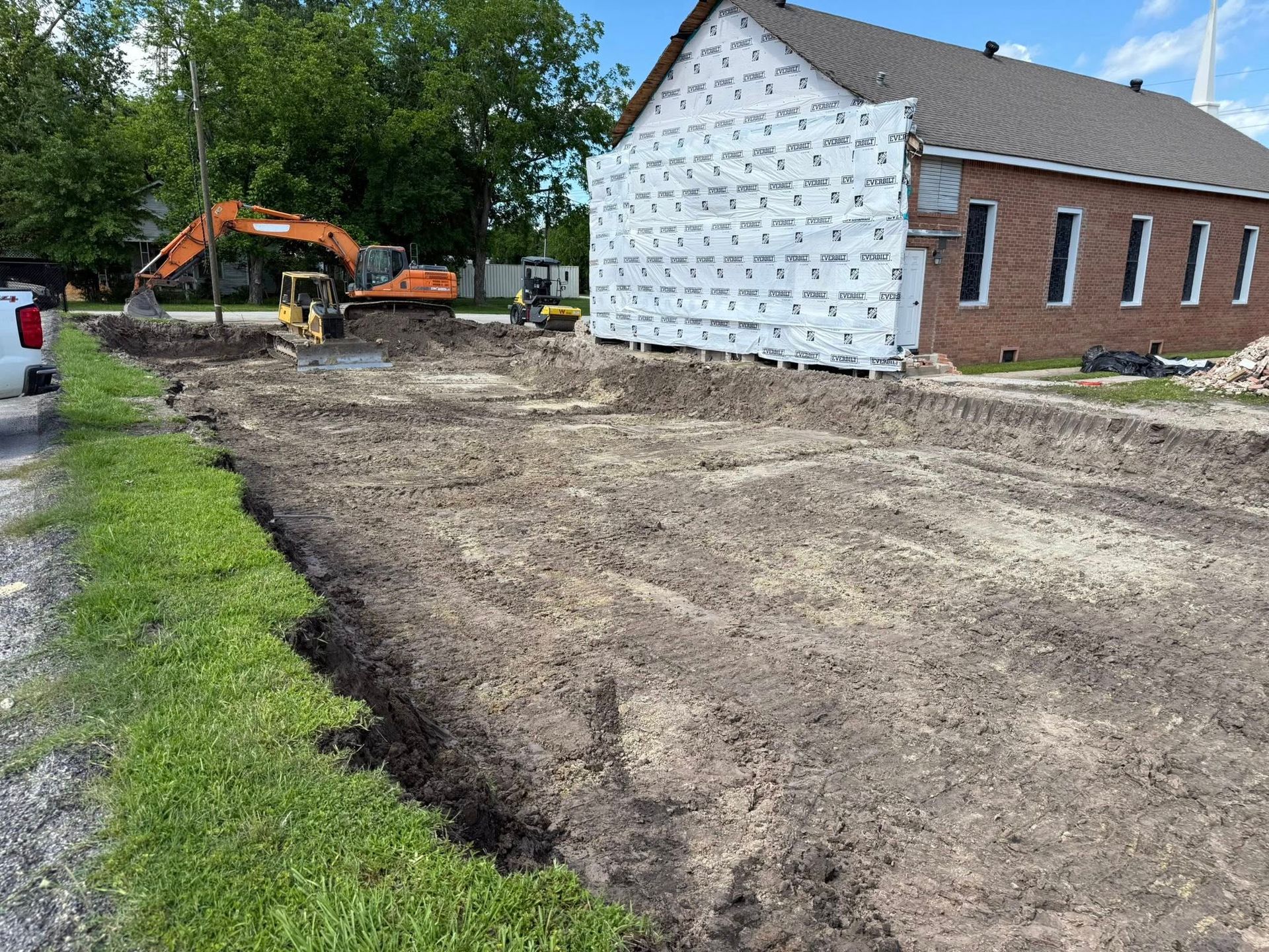 A large brick building is being built next to a dirt field.