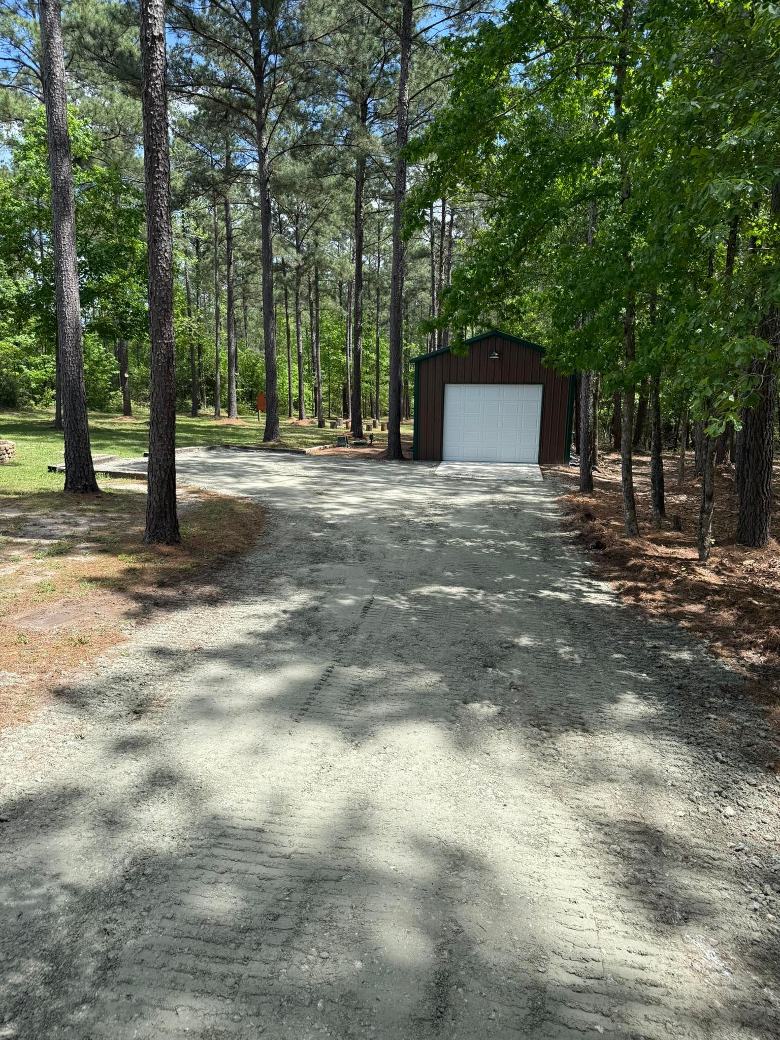 A dirt road leading to a garage in the middle of a forest.