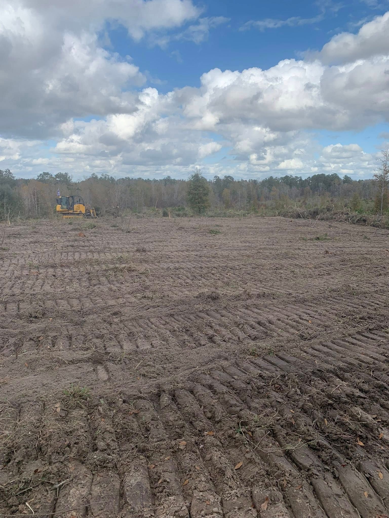 A large muddy field with a blue sky and clouds in the background.