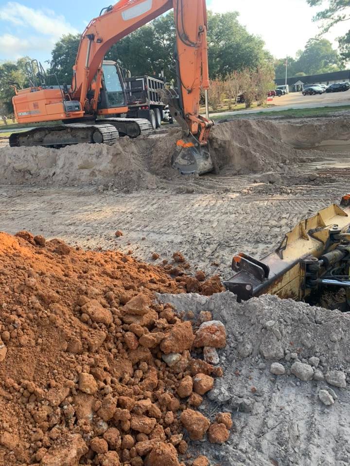 A large orange excavator is digging a hole in the dirt.