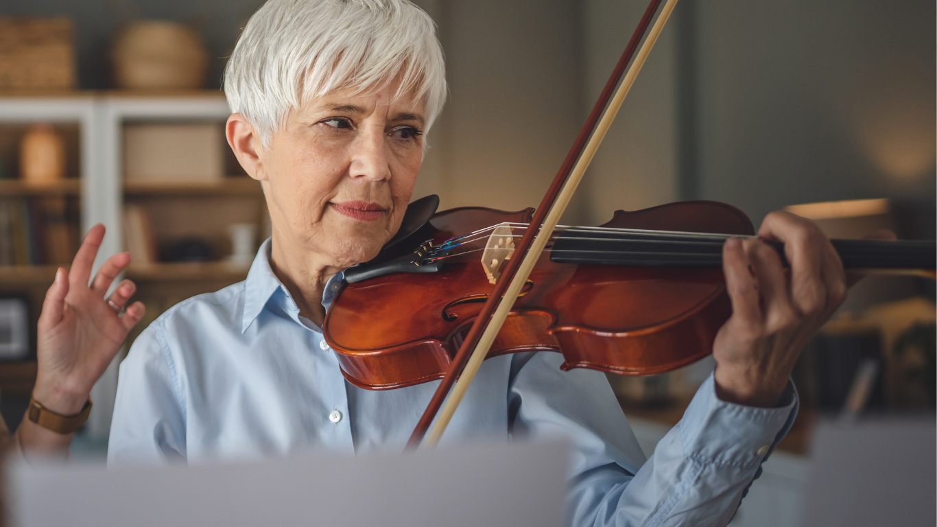 A young girl is playing a violin in front of a wall of guitars.