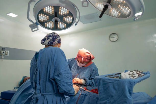 Female surgeon and her instrumentalist suture a woman after performing a caesarean section.
