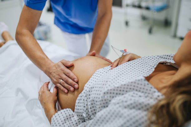 Obstetrician examining pregnant woman in hospital.