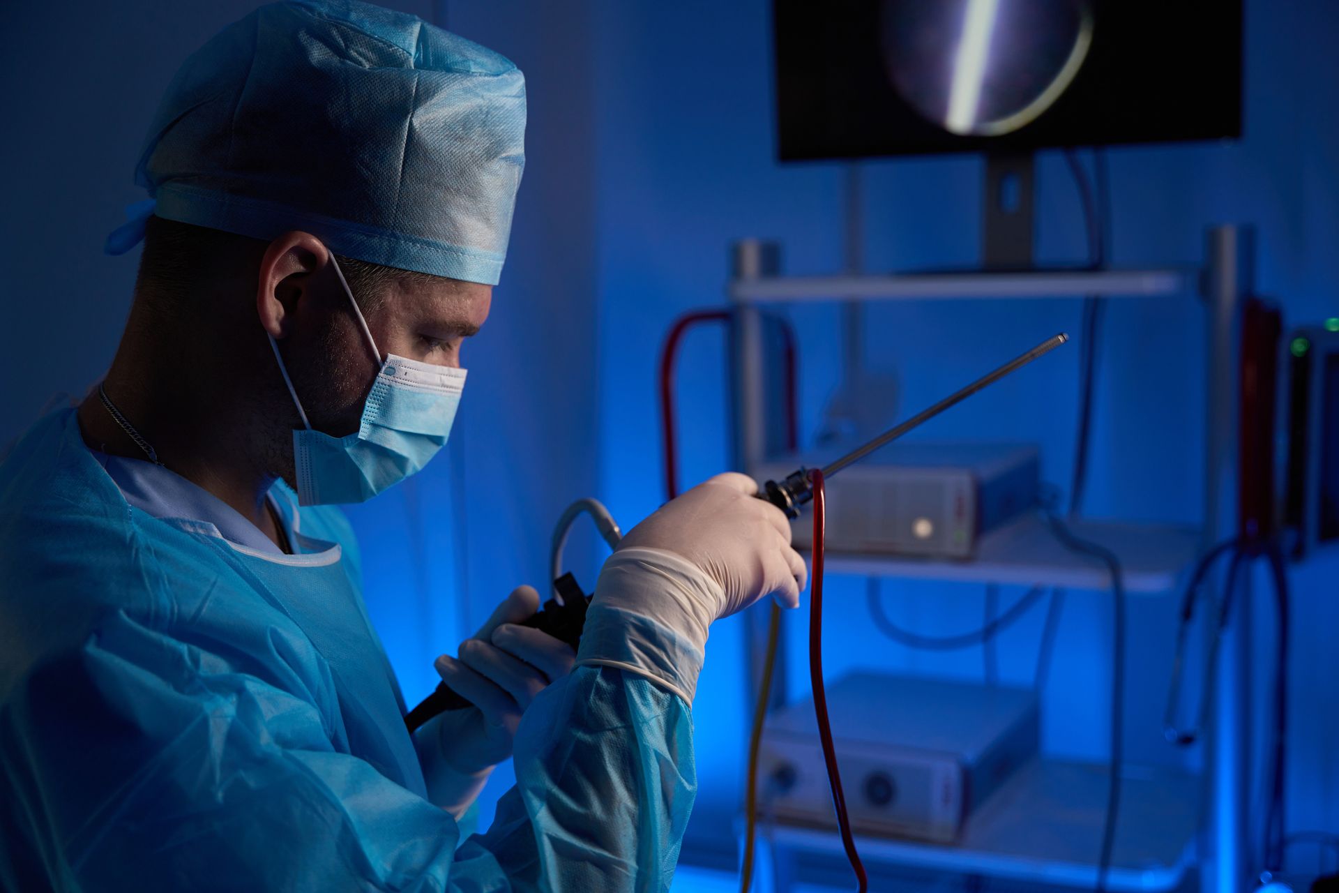 Surgeon in blue scrubs operates laparoscopic tool in medical suite. Surgeon in blue scrubs operates laparoscopic tool in medical suite.