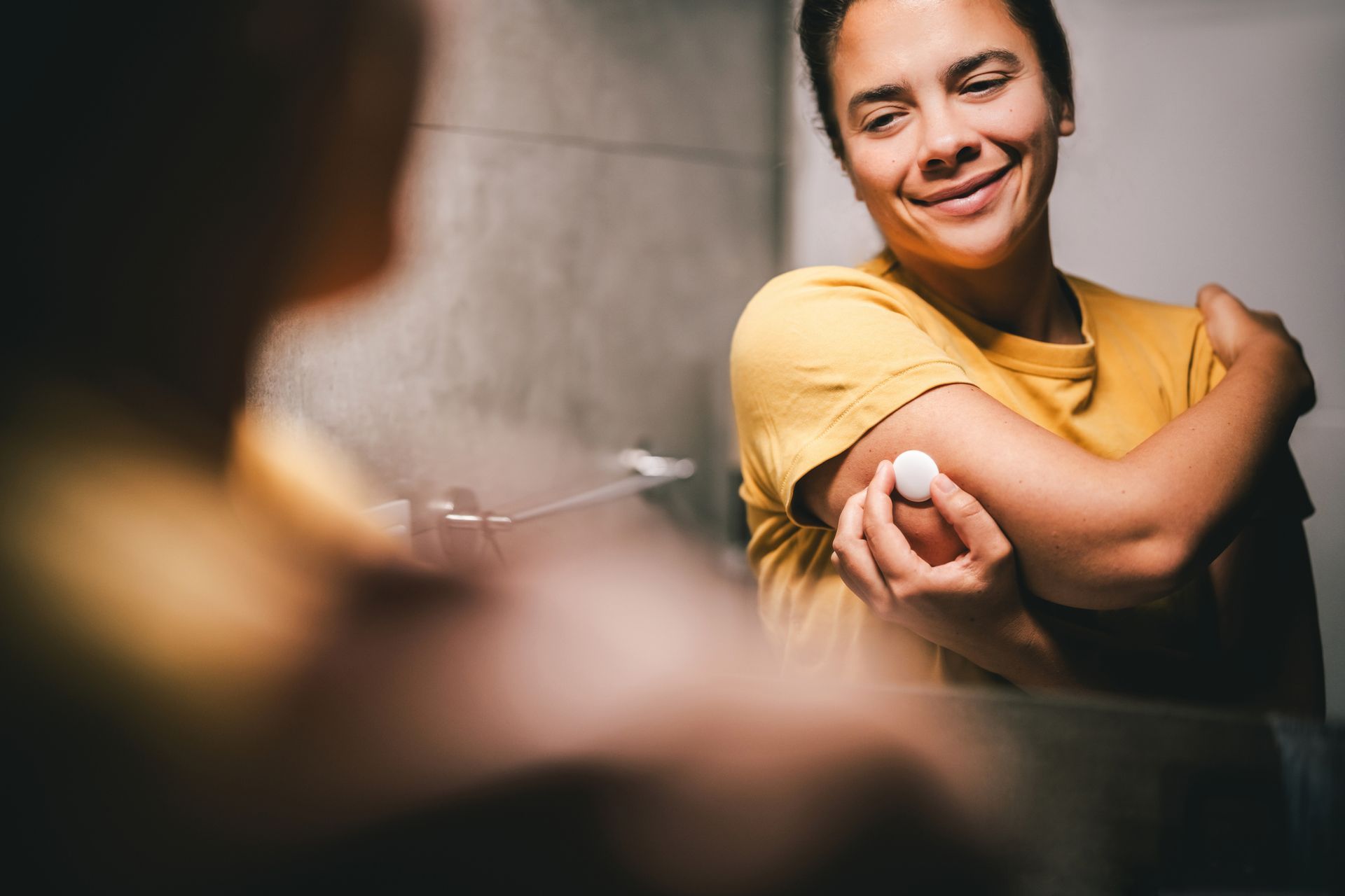 A woman adjusts her PCOS hormone therapy on her arm before showering.