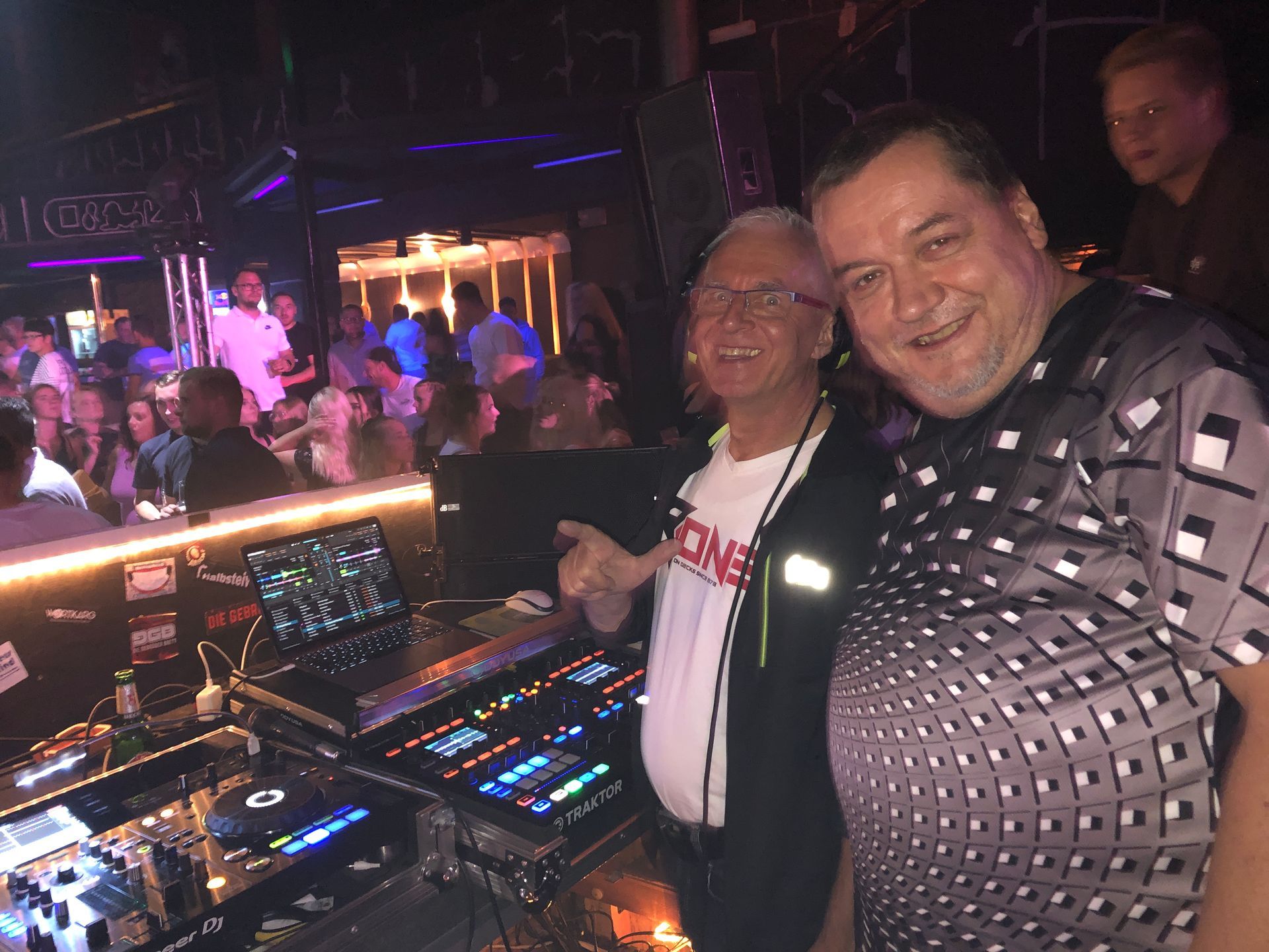 Zwei Männer stehen nebeneinander in einem Club.