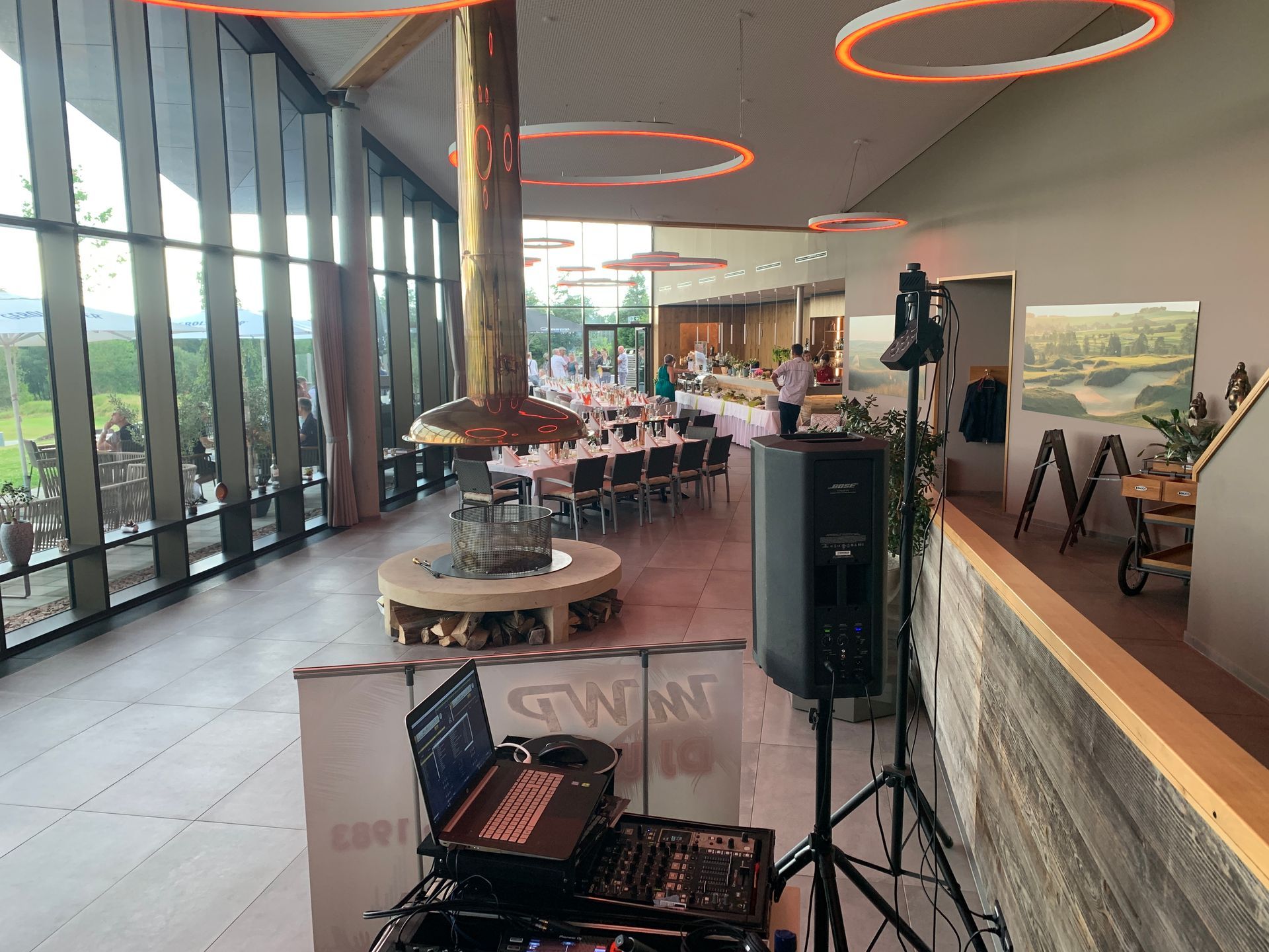 Ein DJ spielt Musik in einem großen Raum mit vielen Fenstern.