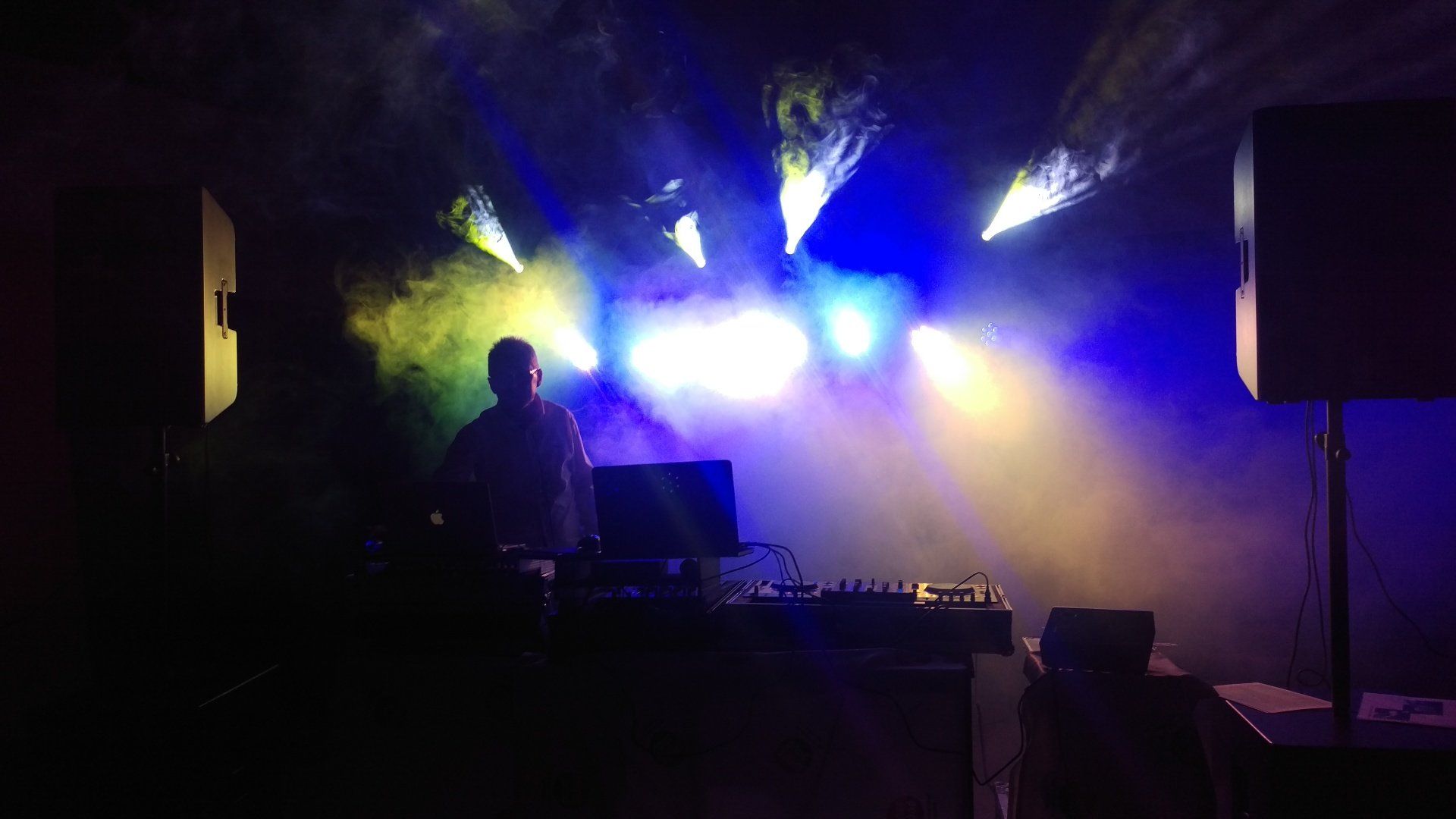 Ein Mann spielt in einem dunklen Raum ein DJ-Set.