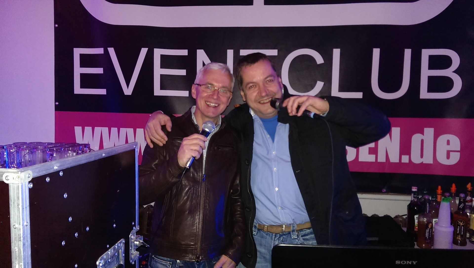 Zwei Männer stehen vor einem Schild mit der Aufschrift „Event Club“