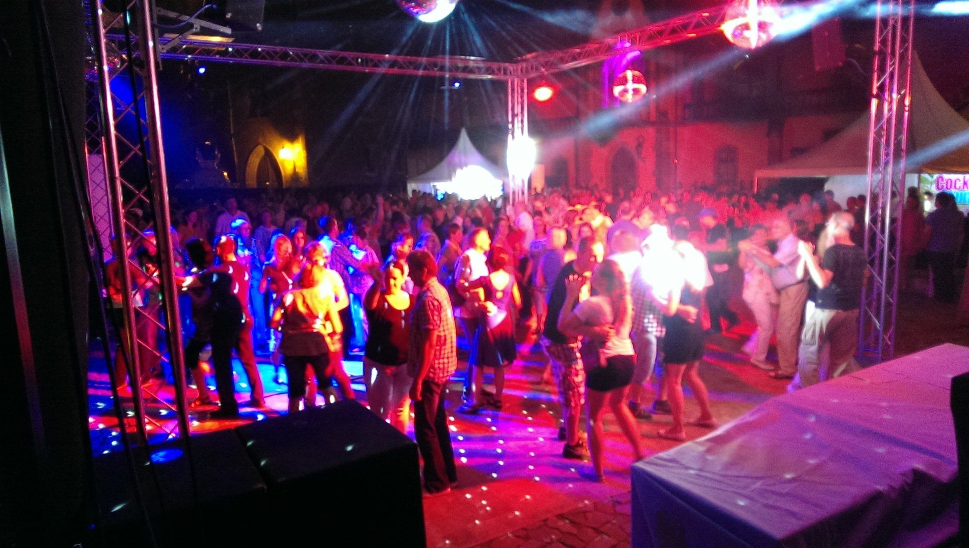 Eine große Gruppe von Menschen tanzt auf einer Tanzfläche bei einer Party.