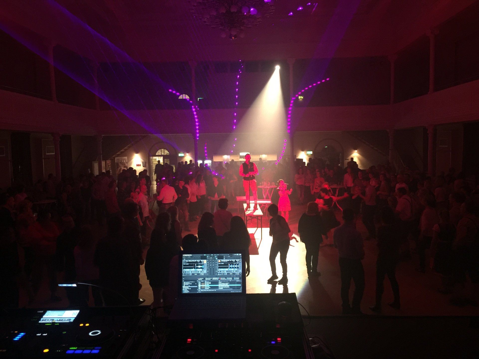 Eine große Menschenmenge tanzt auf einer Party in einem dunklen Raum.