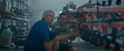 Two men are working on a machine in a factory.