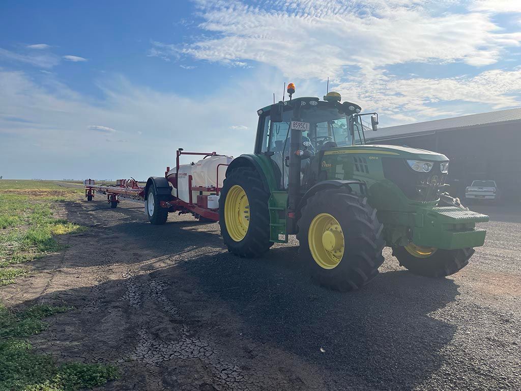A green john deere tractor is parked in a gravel lot.