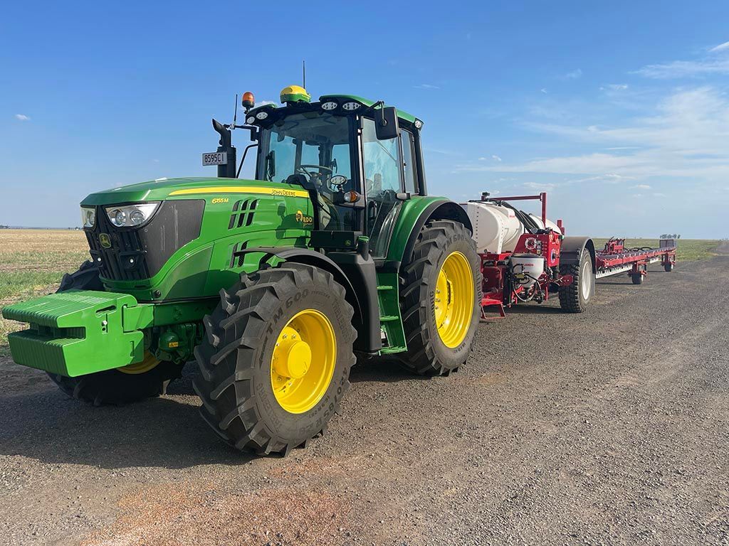 A green and yellow john deere tractor is parked on the side of the road.