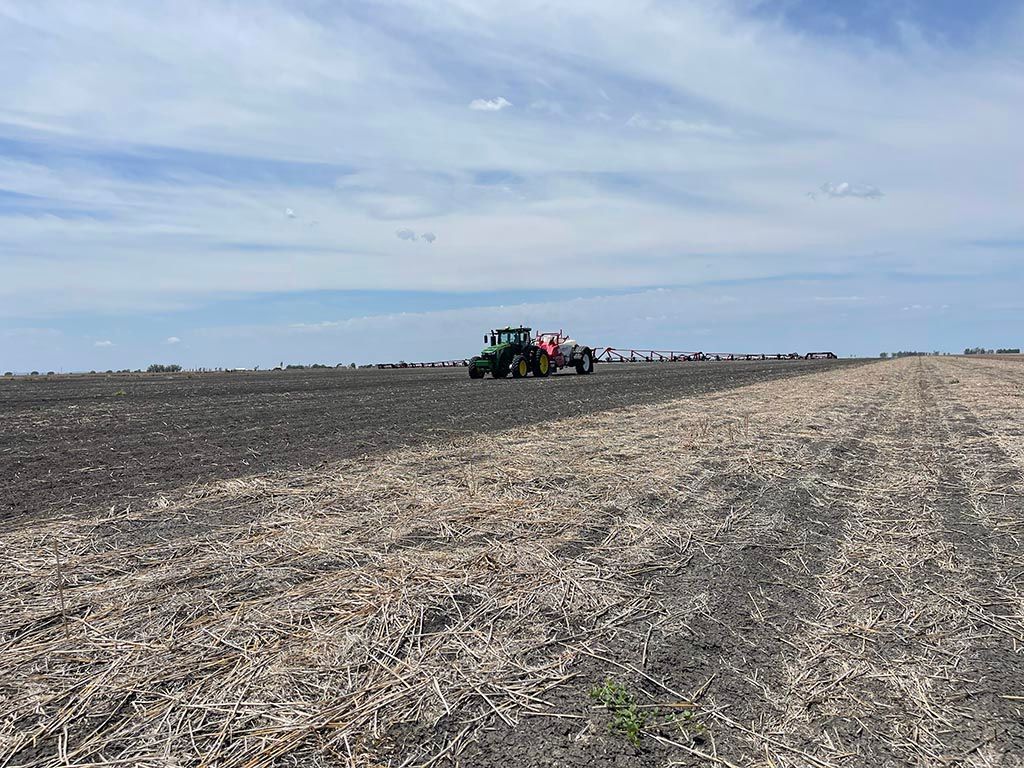 A tractor is plowing a field with a trailer attached to it.