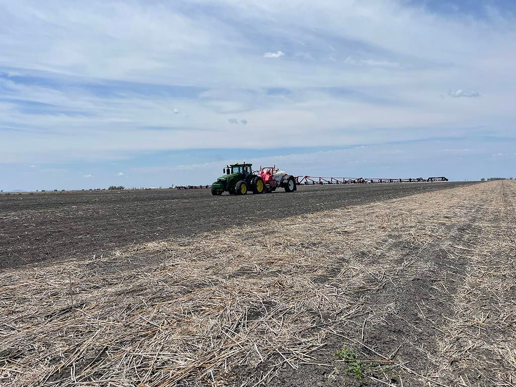 A tractor is plowing a field with a trailer attached to it.