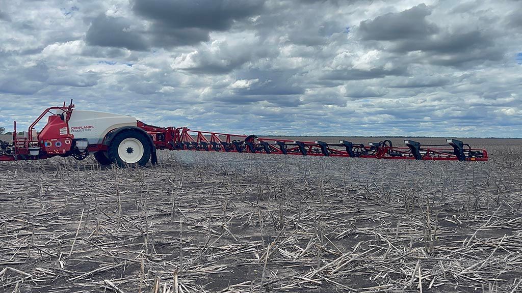 A tractor is plowing a field on a cloudy day.