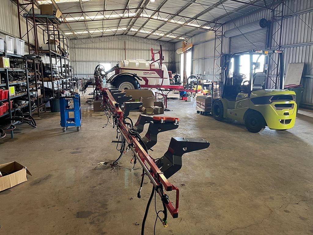 A forklift is parked in a garage next to a tractor.
