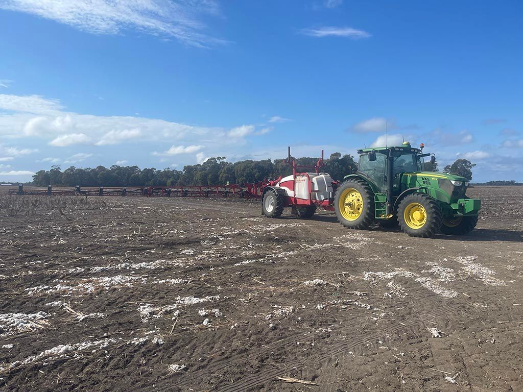 A green and yellow tractor is plowing a field.