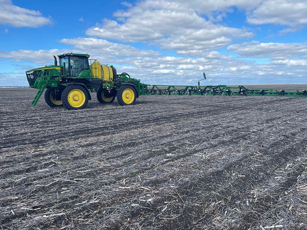 A john deere tractor is spraying a field with a sprayer.