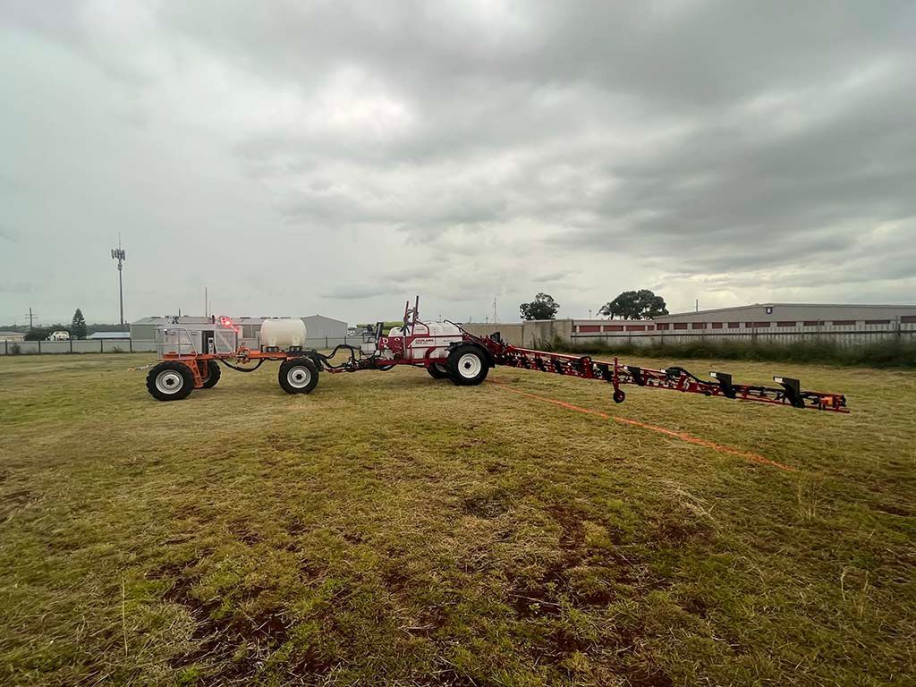 A tractor with a trailer attached to it is parked in a grassy field.