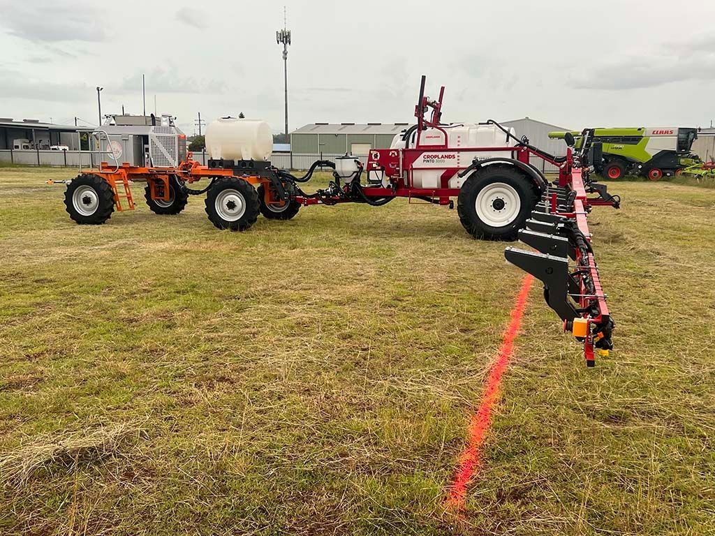 A tractor with a trailer attached to it is spraying a field.