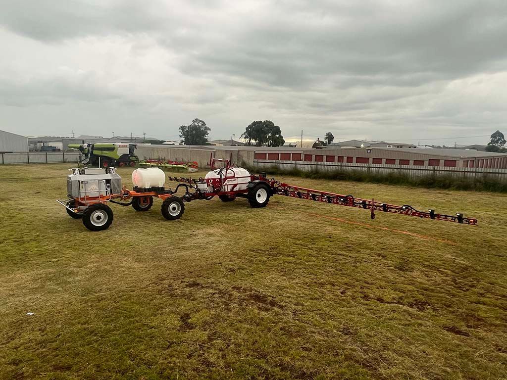 A tractor with a trailer attached to it is spraying a field.