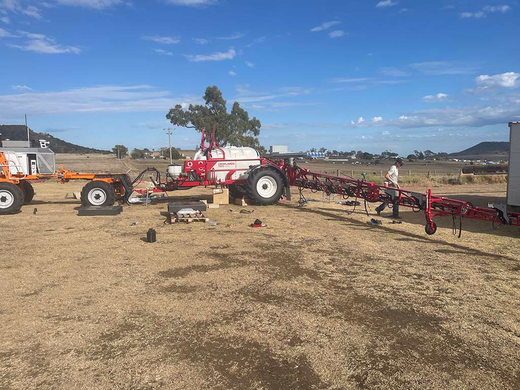 A red tractor is parked in a field next to a trailer.