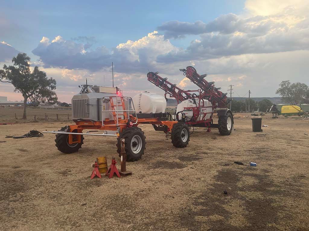 A couple of tractors are parked in a dirt field.