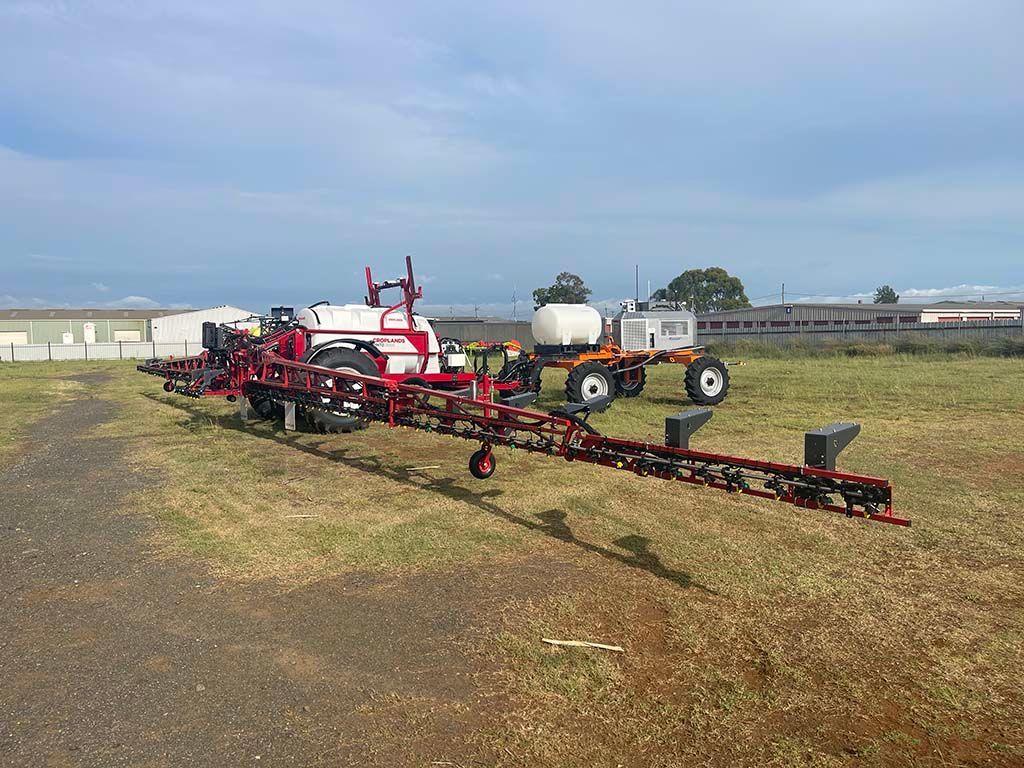 A row of tractors are parked in a grassy field.