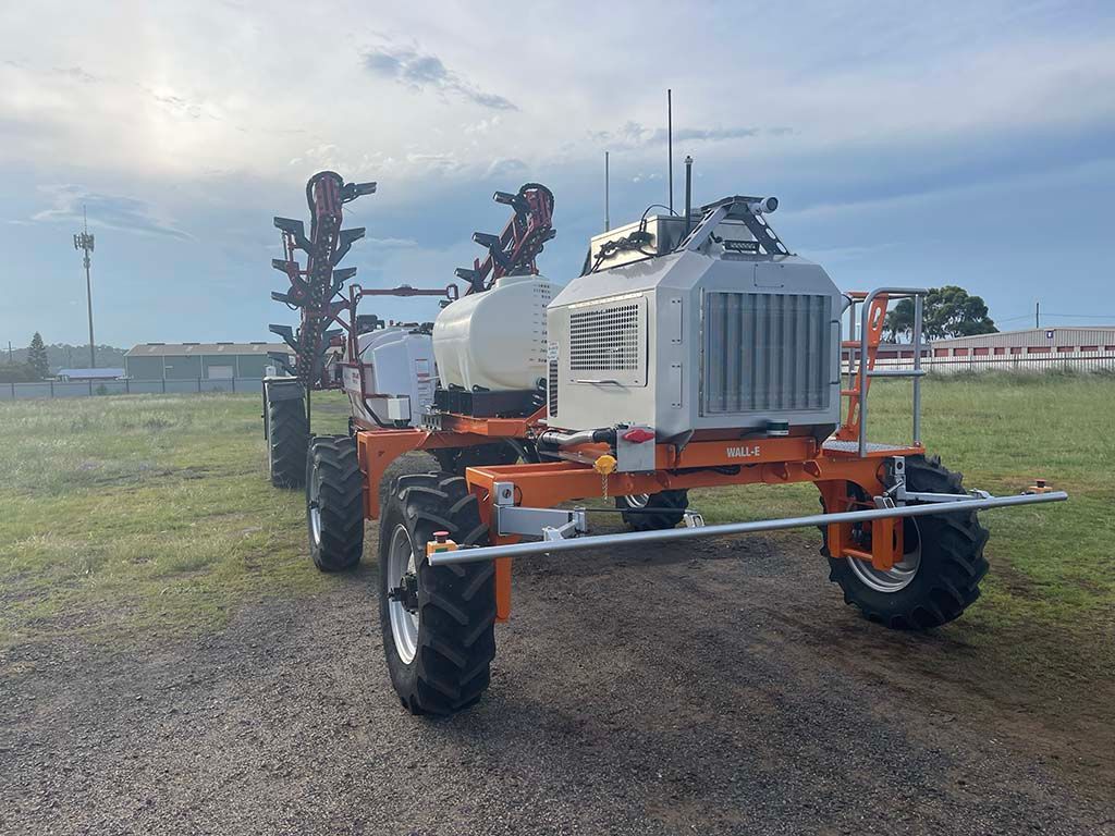 A large orange and white tractor is parked in a grassy field.