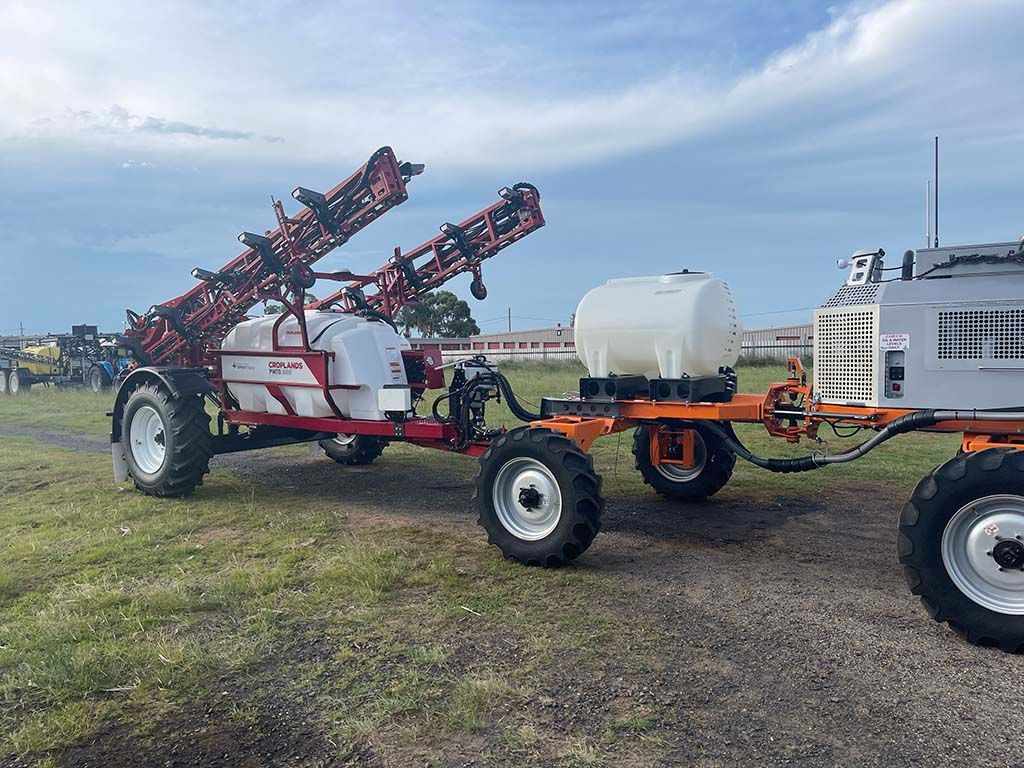 A tractor is pulling a trailer with a sprayer attached to it.