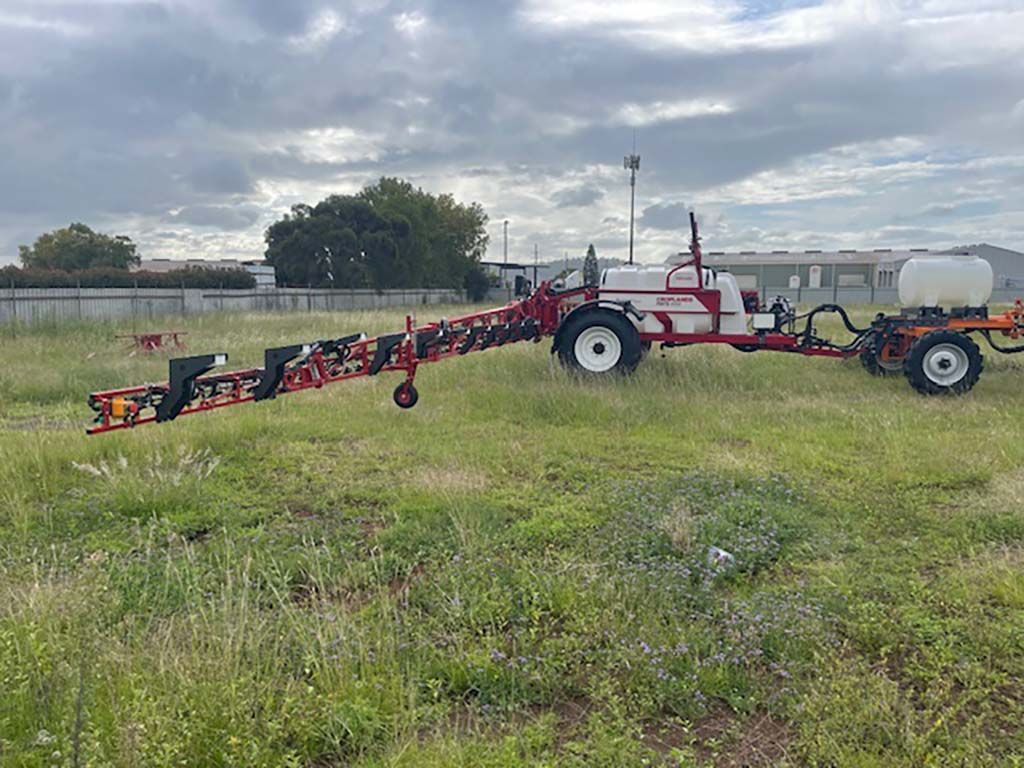 A red and white tractor is parked in a grassy field.