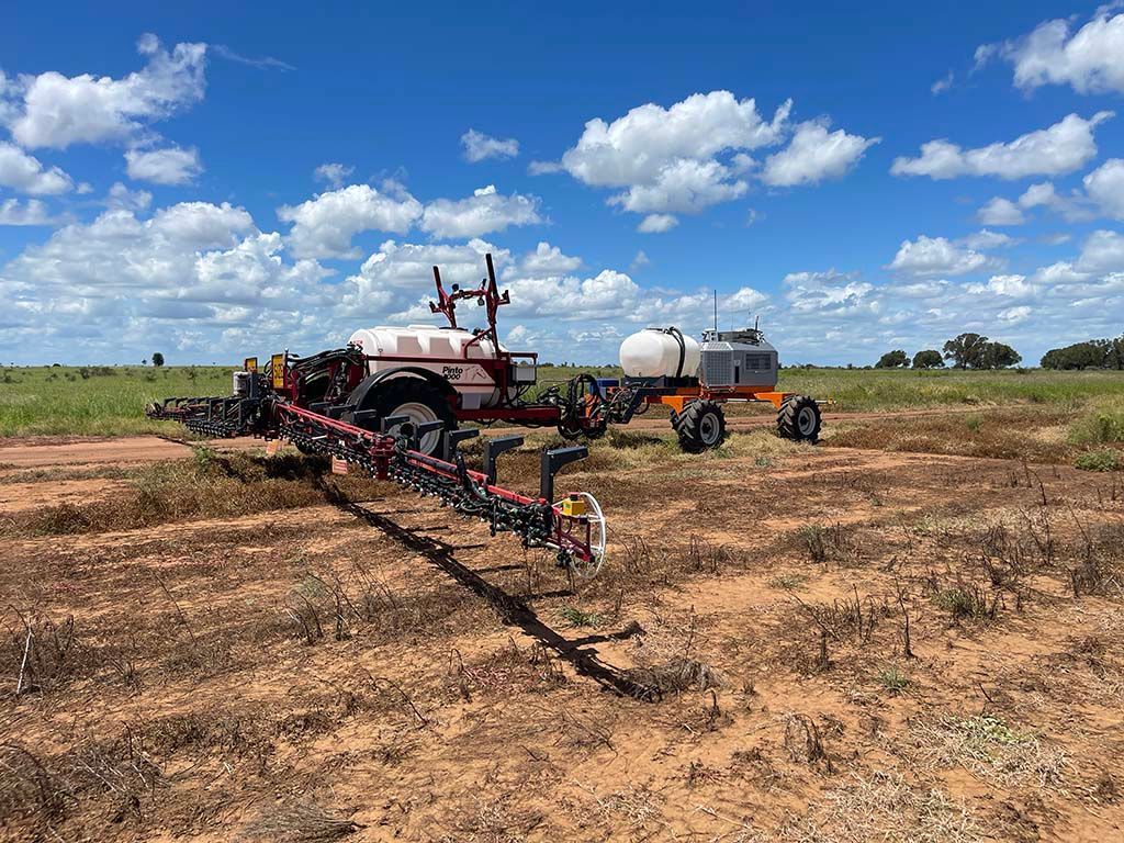 A tractor is spraying a field with a trailer attached to it.