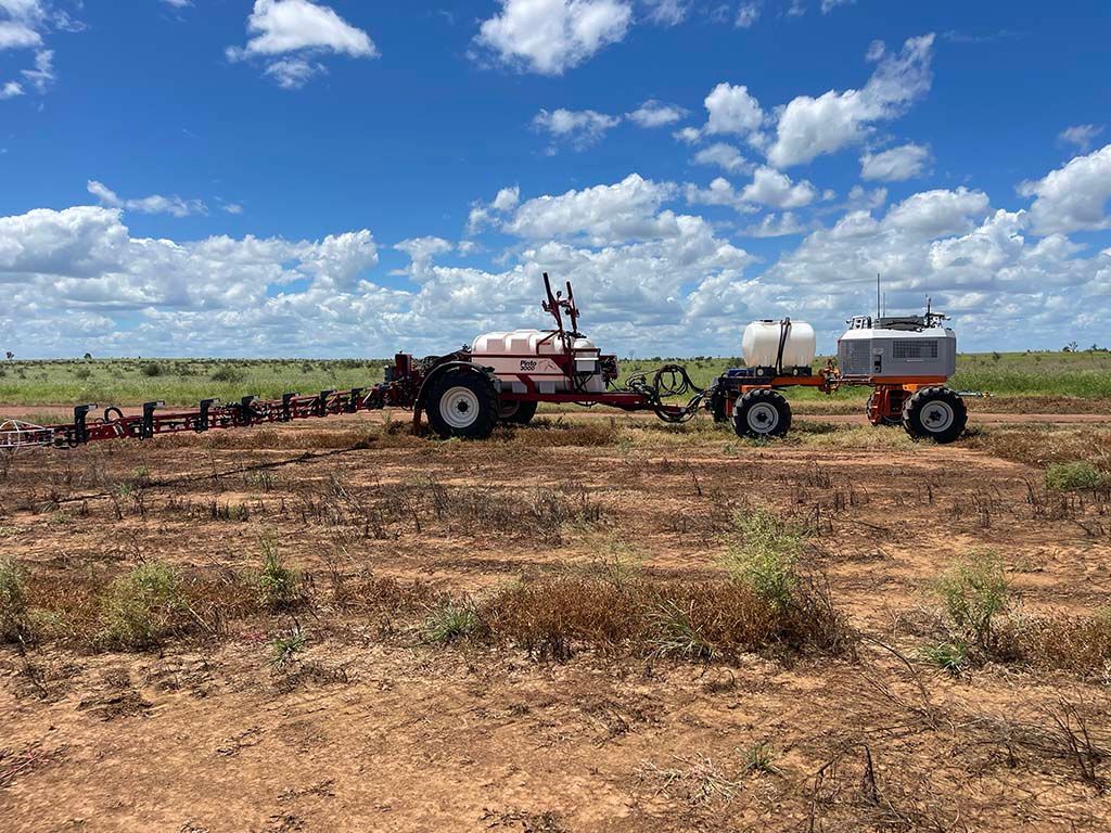 A tractor and trailer are parked in a dry field.