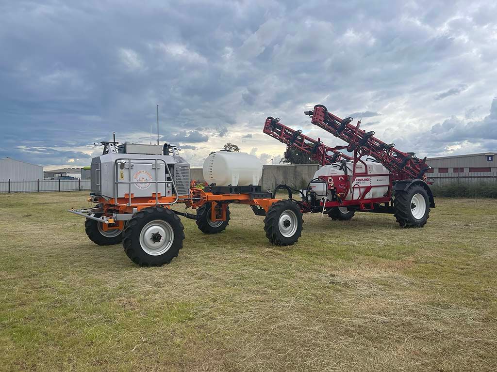 Two sprayers are parked next to each other in a field.