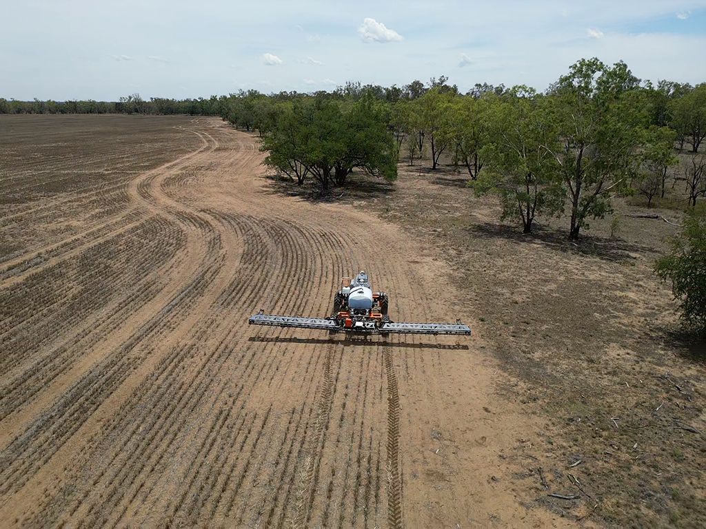 An aerial view of a small plane spraying a field.