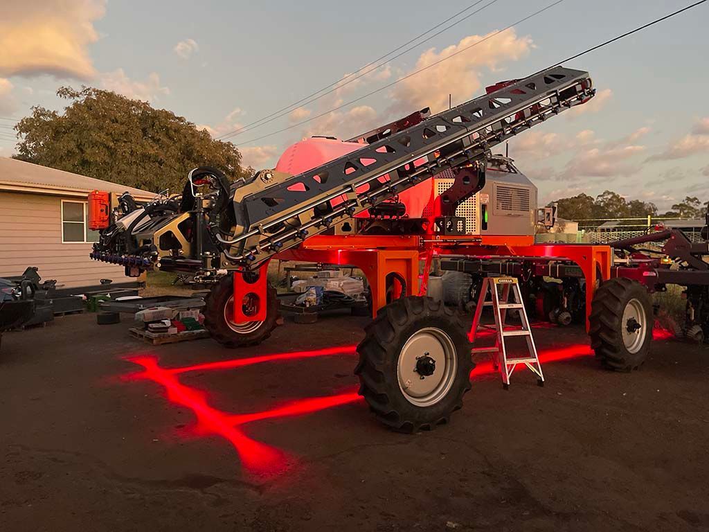 A tractor is parked in a parking lot with red lights on the wheels.