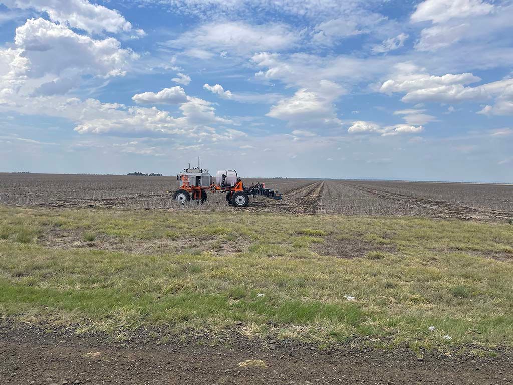 Two tractors are plowing a field on a sunny day.