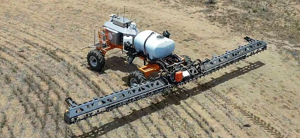 An aerial view of a robotic tractor spraying a field.