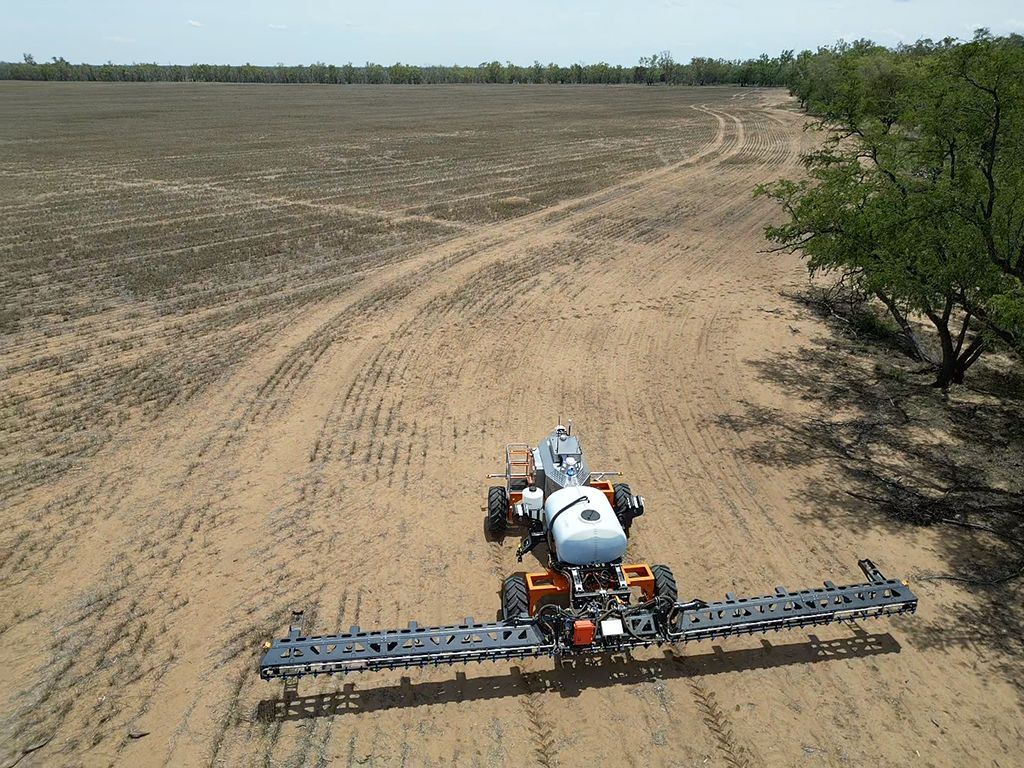 An aerial view of a tractor spraying a field with a sprayer.