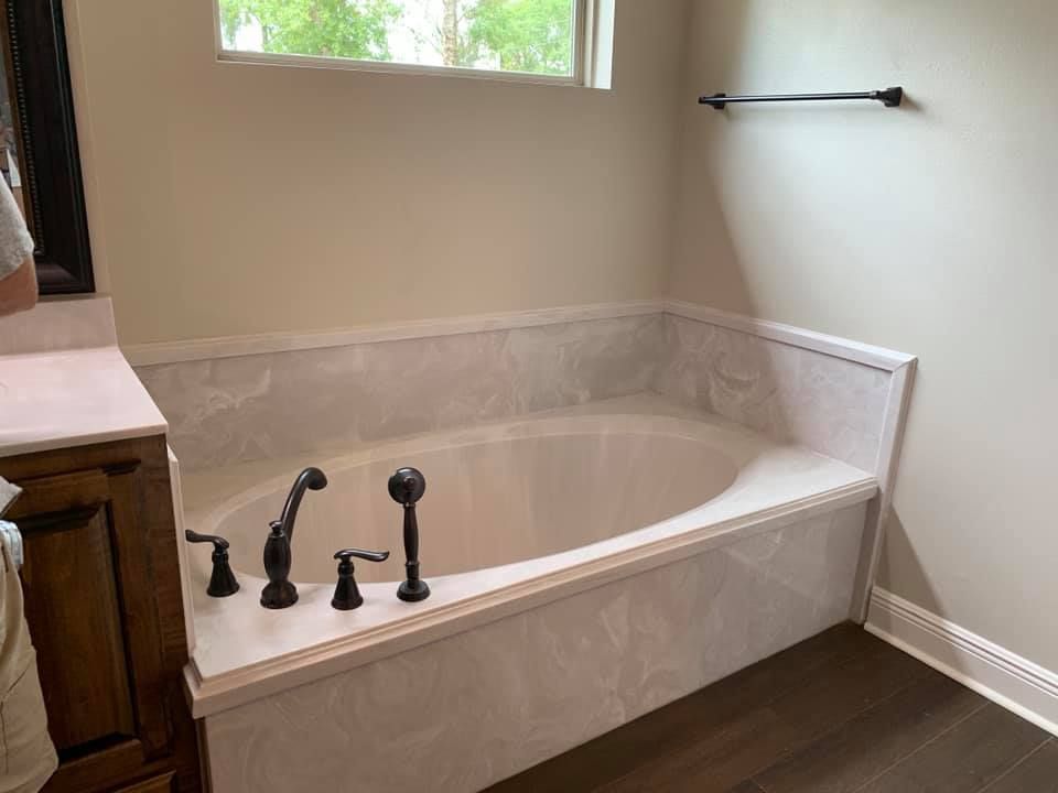 A bathtub in a bathroom next to a window.