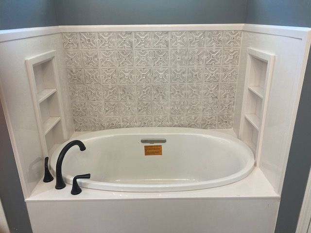 A bathtub with a faucet and shelves in a bathroom.